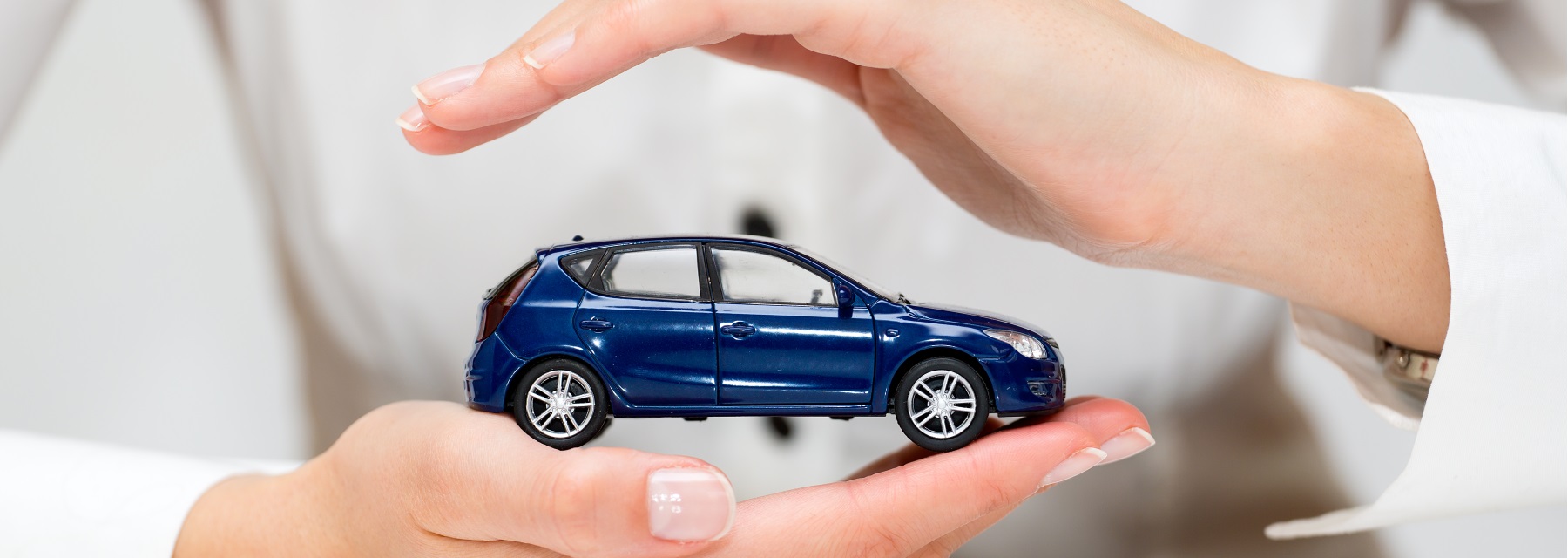 two hands holding miniture blue car